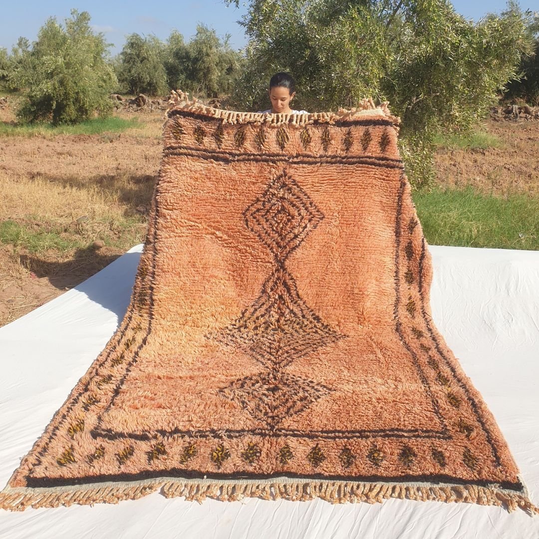 Warda luxurious Beni Mrirt Moroccan rug in terracotta and rust tones with diamond Berber motifs, held outdoors in Morocco — handmade wool Berber carpet 6x9 ft